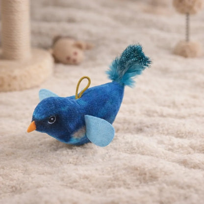 Blue plush chirping bird cat toy with an orange beak, light blue wings, and a fluffy blue tail on a beige rug.