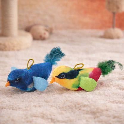 Two plush bird cat toys, one blue and one colorful, with feathered tails and orange beaks on a cream rug.