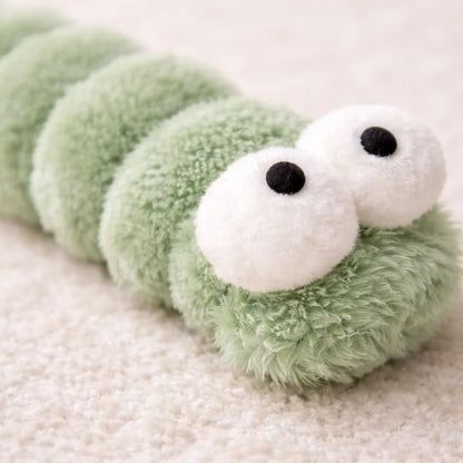 Close-up of a soft, plush green caterpillar catnip kicker toy with large white eyes.