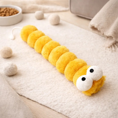Bright yellow plush caterpillar catnip kicker toy with white eyes on a cream rug.