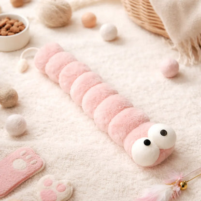 Pink plush caterpillar catnip kicker toy with large eyes on a cream rug.