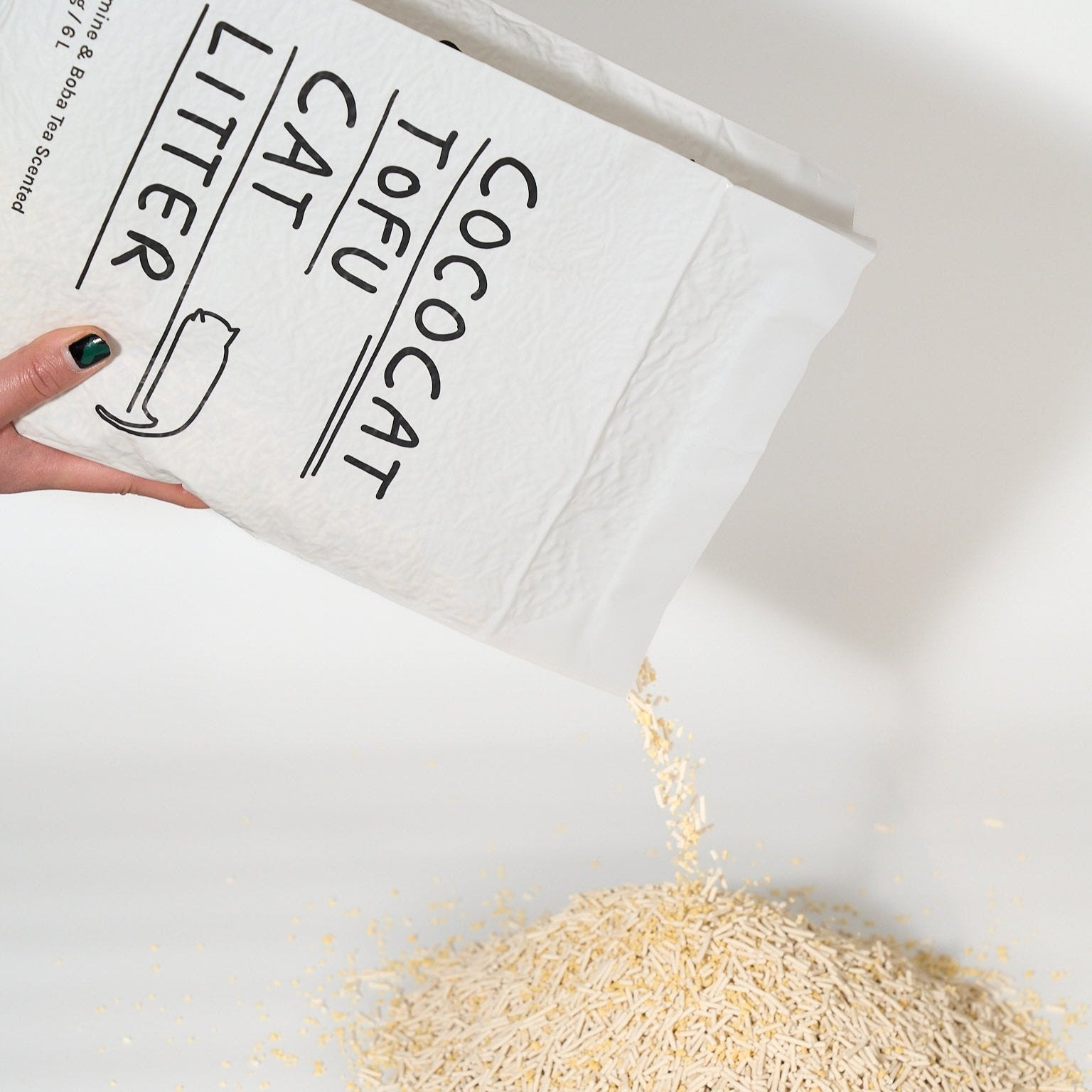 Cococat Tofu Cat Litter being poured from a white bag onto a white surface.