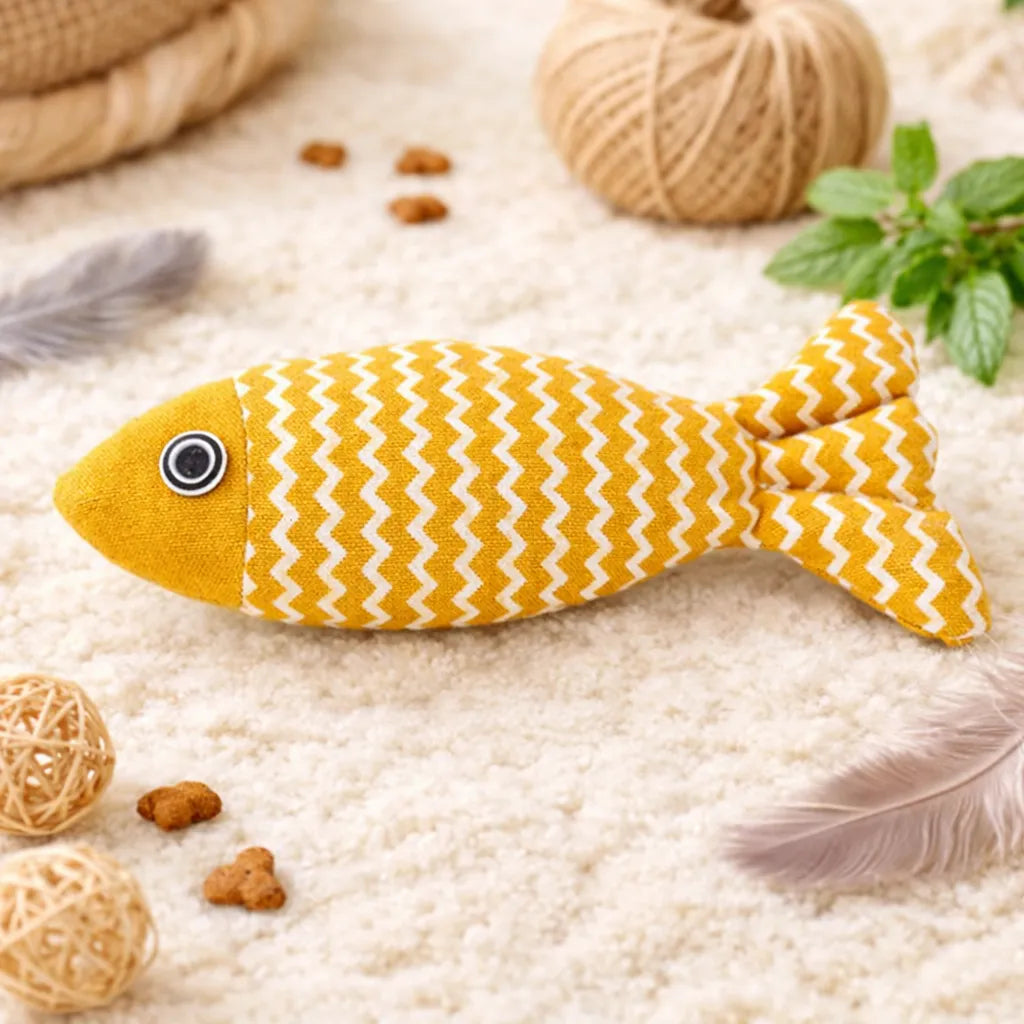 Yellow fish-shaped catnip toy with white zigzag pattern, black eye, on a fluffy rug.