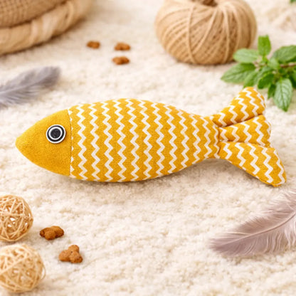 Yellow fish-shaped catnip toy with white zigzag pattern, black eye, on a fluffy rug.