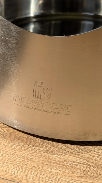 Fussy Cat round stainless steel litter box with engraved logo on a wooden floor.