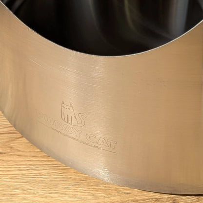 Close-up of a graded Fussy Cat round stainless steel litter box with light cosmetic defects and logo.