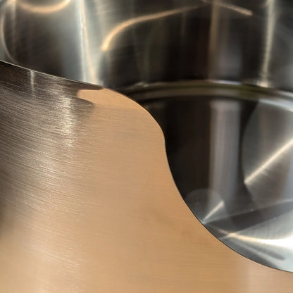 Close-up of a graded Fussy Cat round stainless steel litter box with a brushed finish and light cosmetic defects.