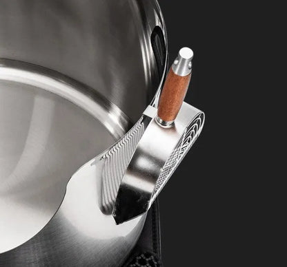 Close-up of a premium round stainless steel litter box with a matching metal scoop featuring a wooden handle.