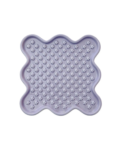 Light purple ceramic Fussy Cat slow feeder with flower-shaped divots for healthy eating.