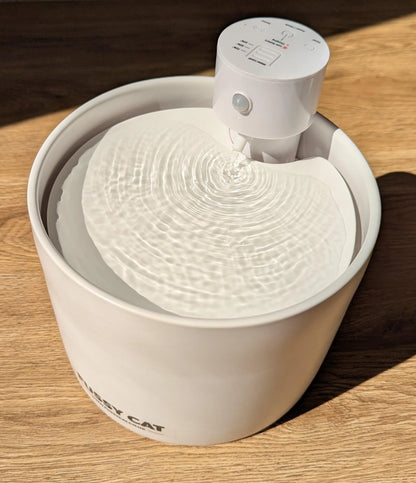 White ceramic Fussy Cat water fountain with flowing water, motion sensor, and control panel.