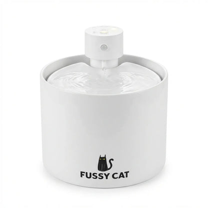White ceramic Fussy Cat water fountain with a black cat logo, flowing water, and a wireless design.