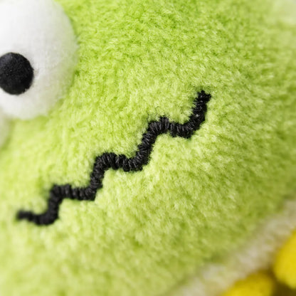Close-up of a soft, fuzzy green bug plush cat toy with a white eye and black antennae.