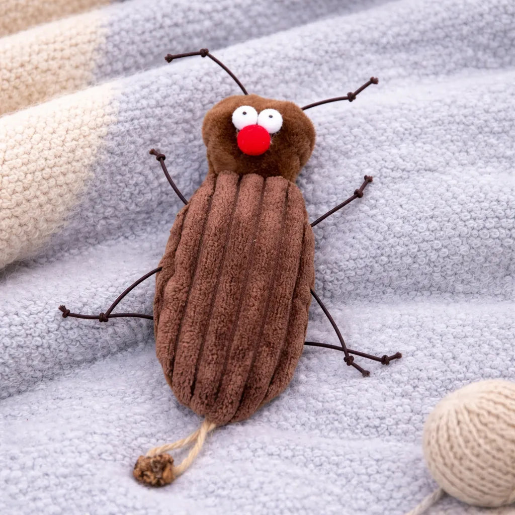 Brown plush cockroach cat toy with red nose, white eyes, and wire legs on a grey knitted blanket.