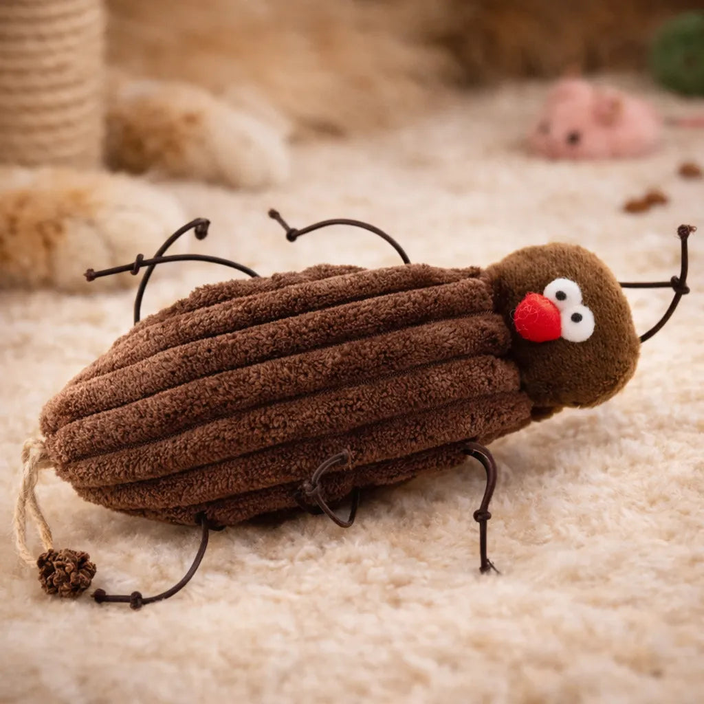 Brown plush cockroach cat toy with red nose, white eyes, and wire legs on a beige rug.