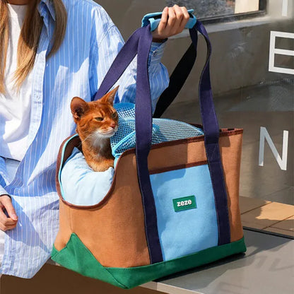 ZEZE brown and turquoise canvas pet carrier with an orange cat looking out, held by a person.