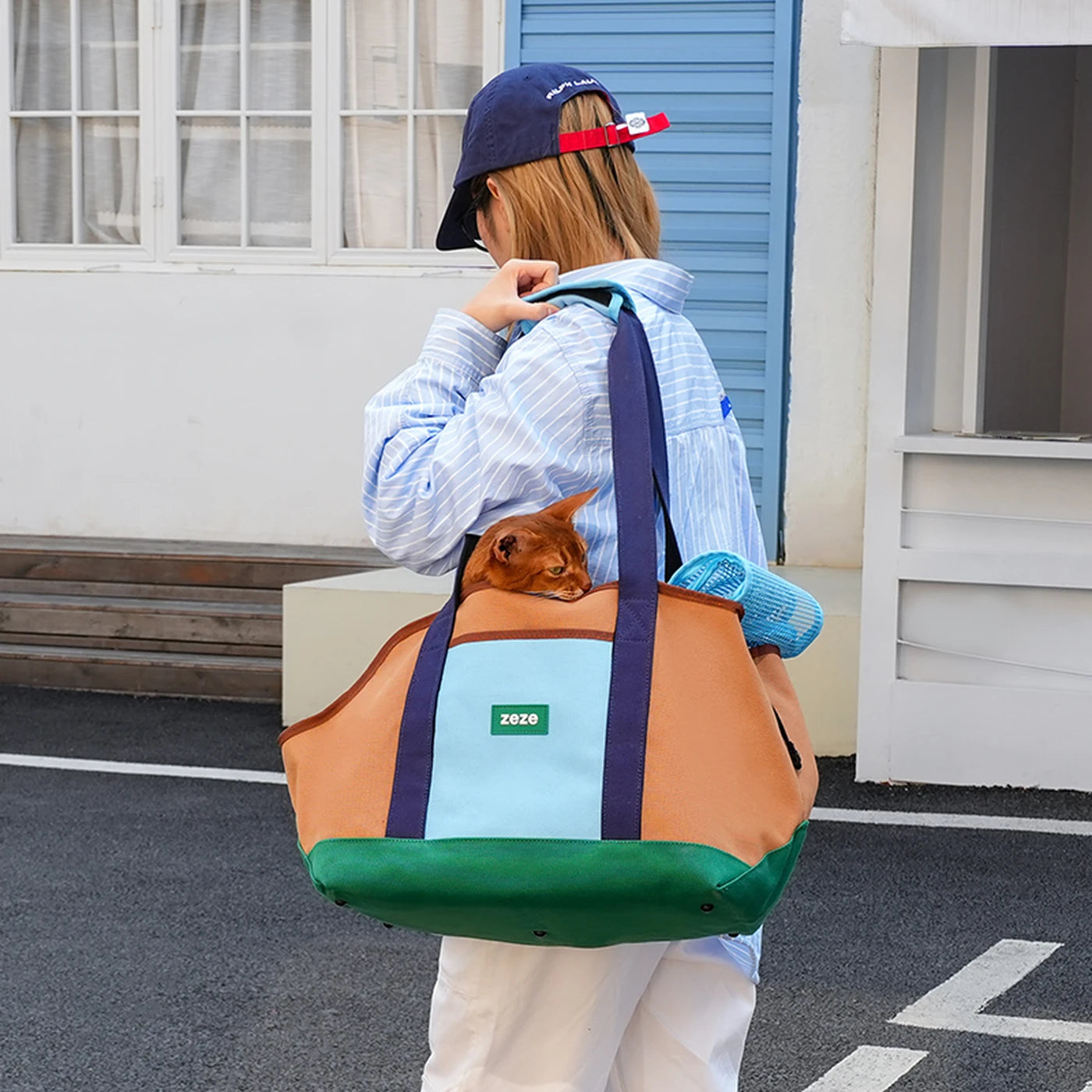 ZEZE brown, turquoise, and green canvas pet carrier with a small dog inside, carried by a person.