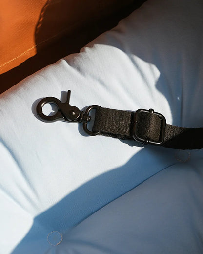 Close-up of a black safety buckle and strap inside a brown and turquoise canvas pet carrier.
